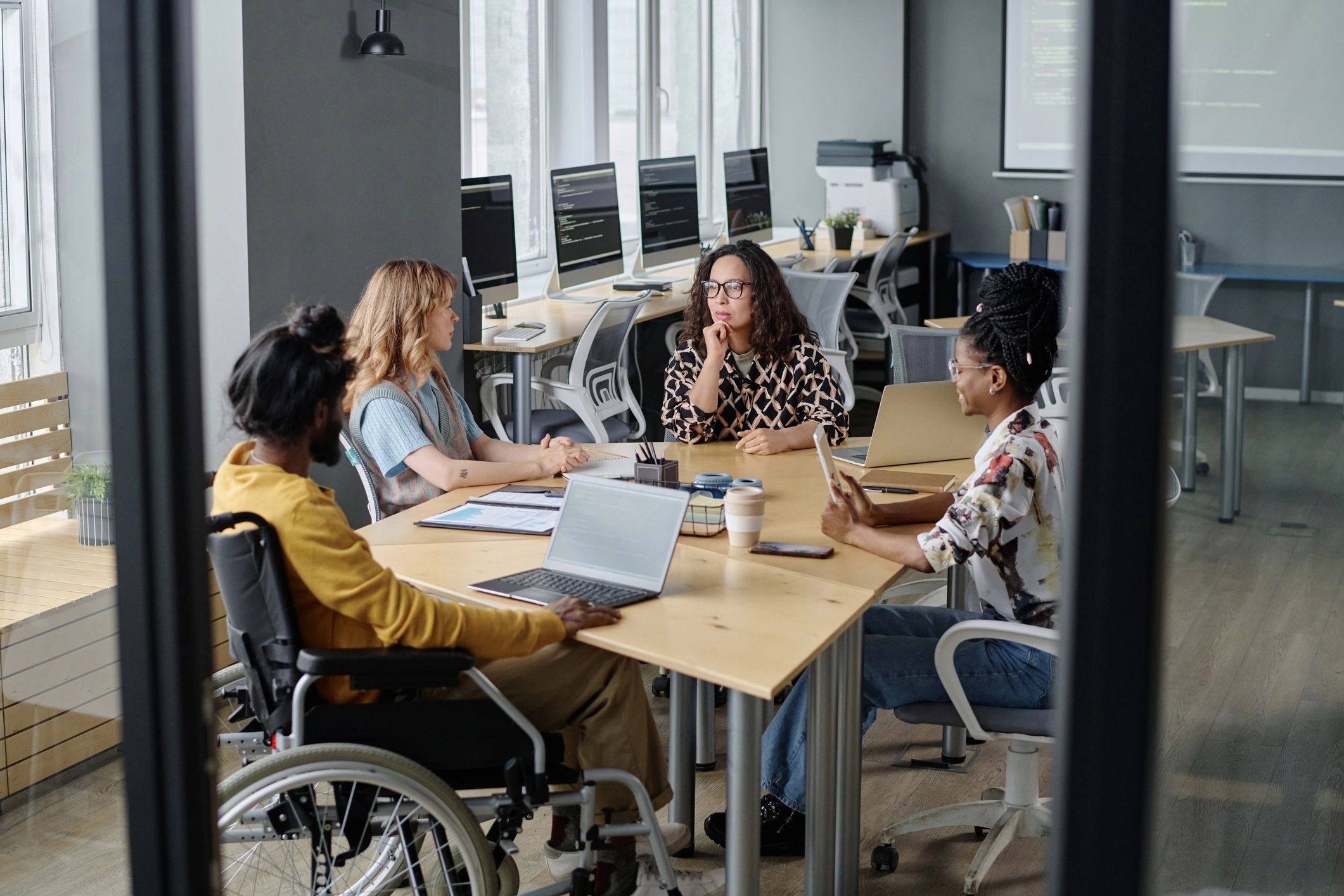 Equipo diverso colaborando en una mesa de trabajo con dispositivos y pantallas